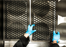 Hands shown from above moving a tray on top of a metal surface. 