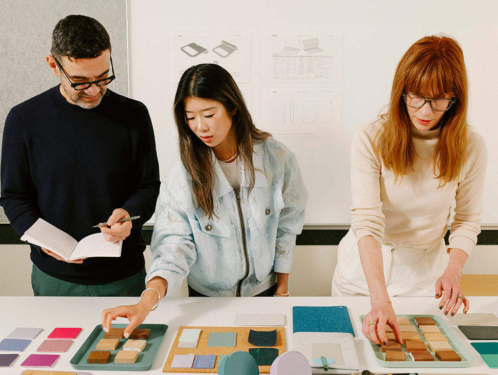 Three people stand over a table with Amazon devices and design materials.