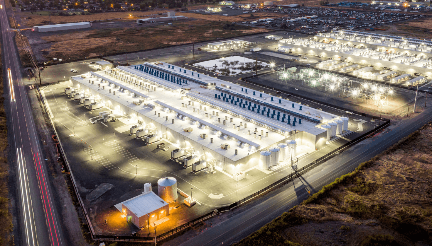 An aerial view of an Amazon facility with lights on at night. 