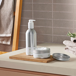 Body wash and body cream containers sit neatly on a bathroom sink countertop.