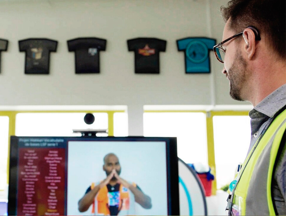 A person stands in front of a sign language video station.