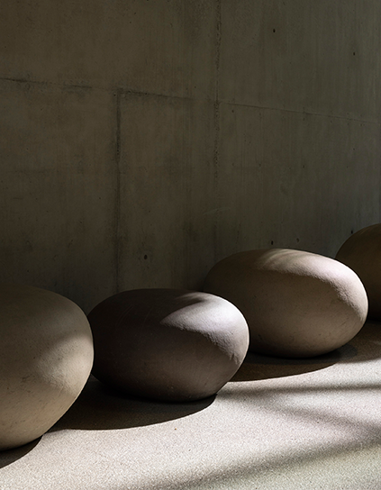 Partially shaded concrete stones against a concrete wall.