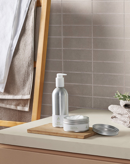 Body wash and body cream containers sit neatly on a bathroom sink countertop.