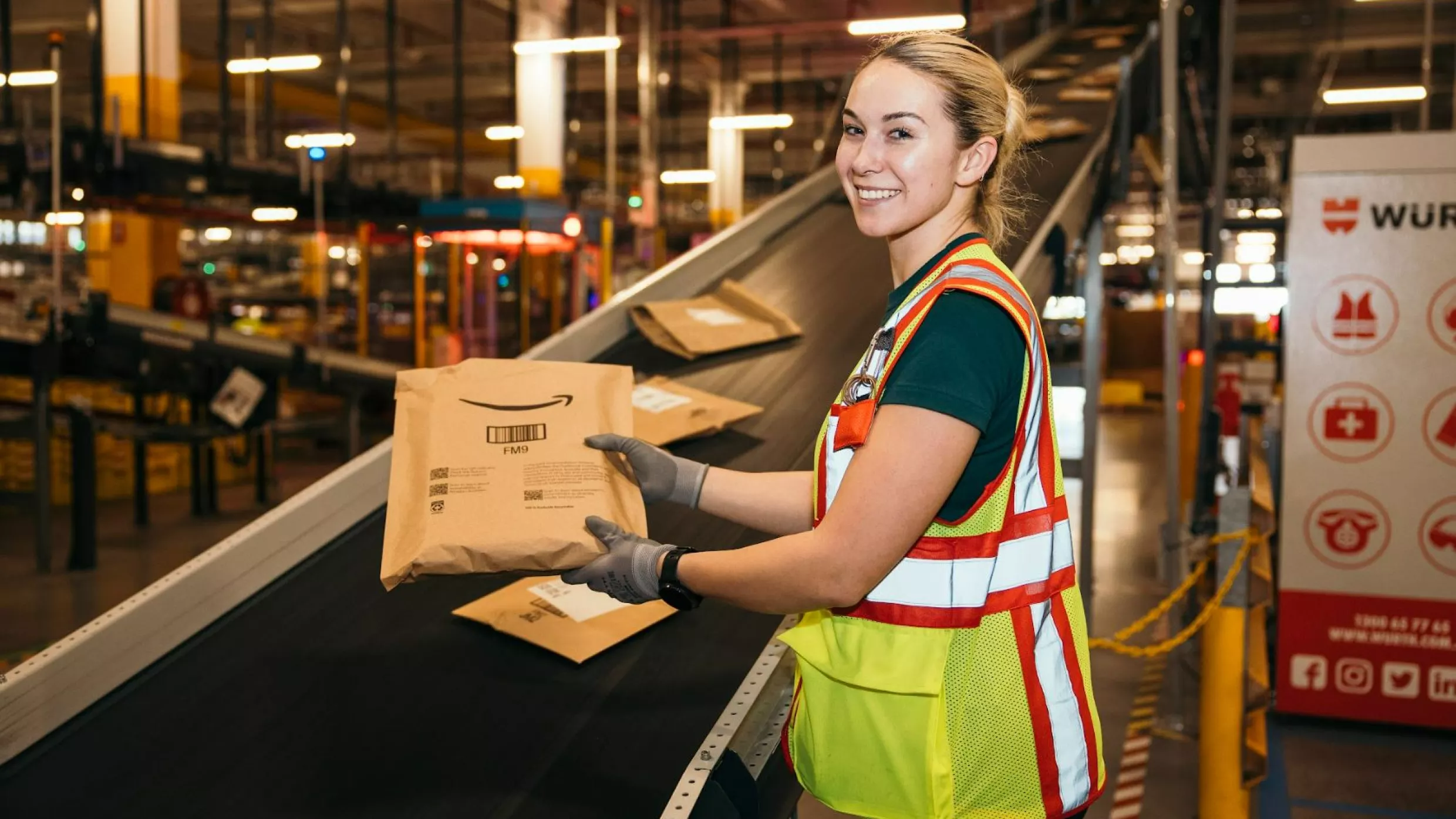 Two people stand in front of recyclable materials in a recycling facility.